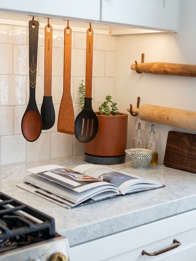 A kitchen counter with hanging utensils, a terracotta planter, and an open cookbook